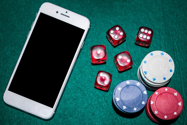 Overhead view of poker table with red dices, casino chips and smartphone
